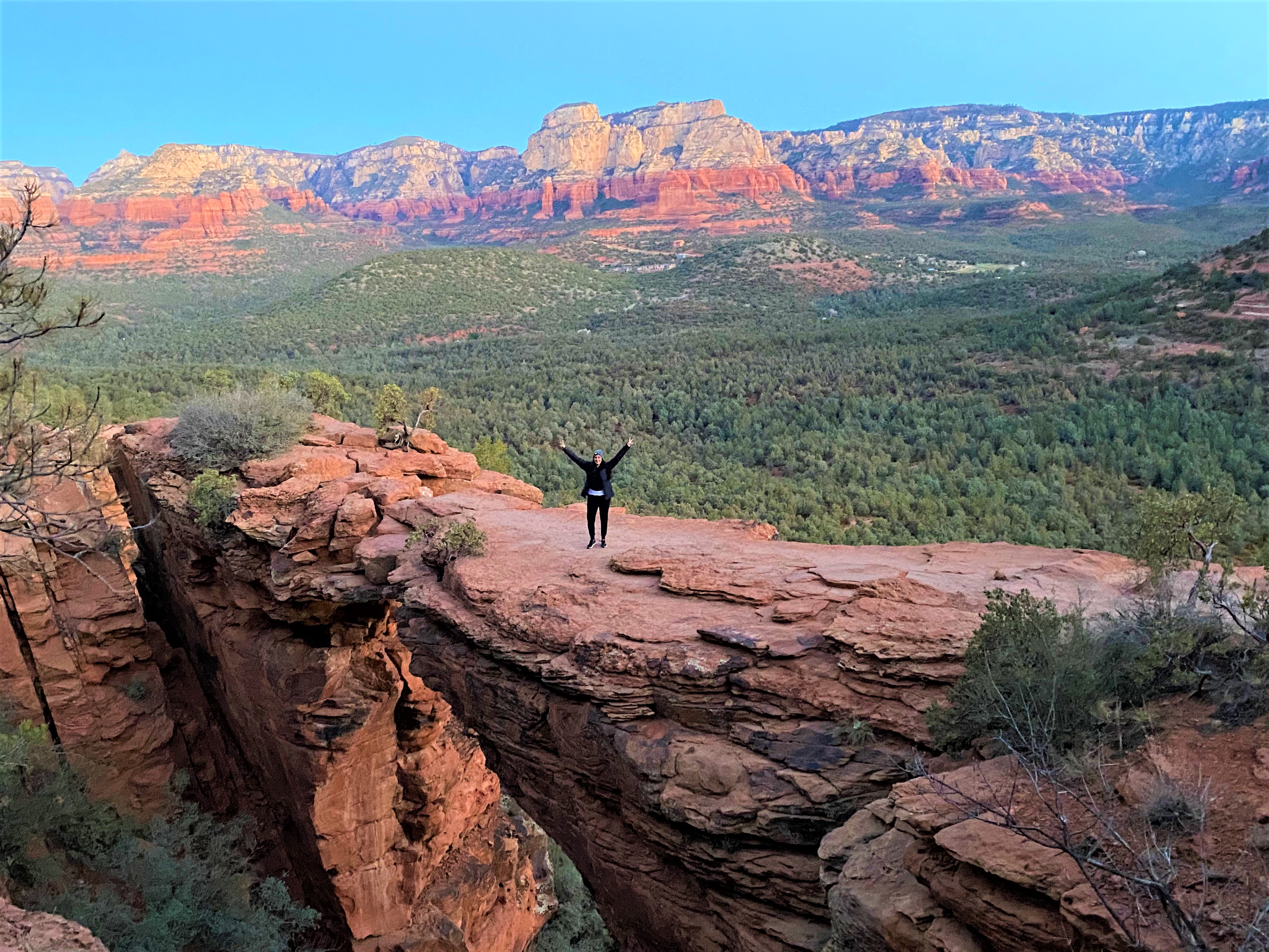 Woman standing on Devil's Bridge with both her arms up and giving the peace sign