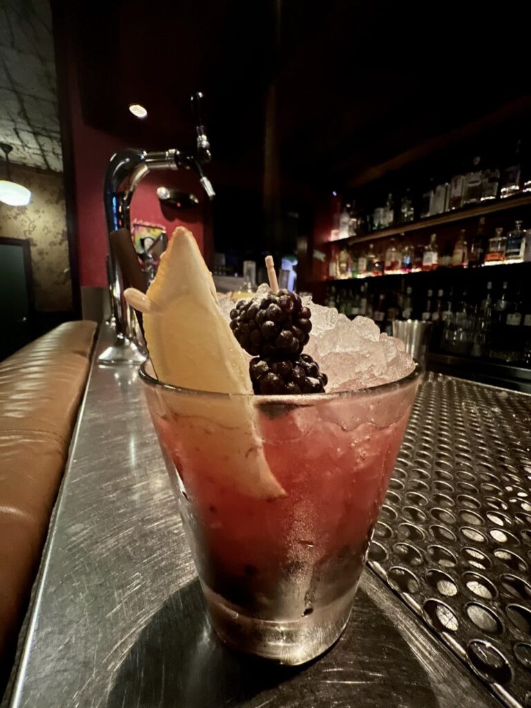 a cocktail with blackberries and lemon slice