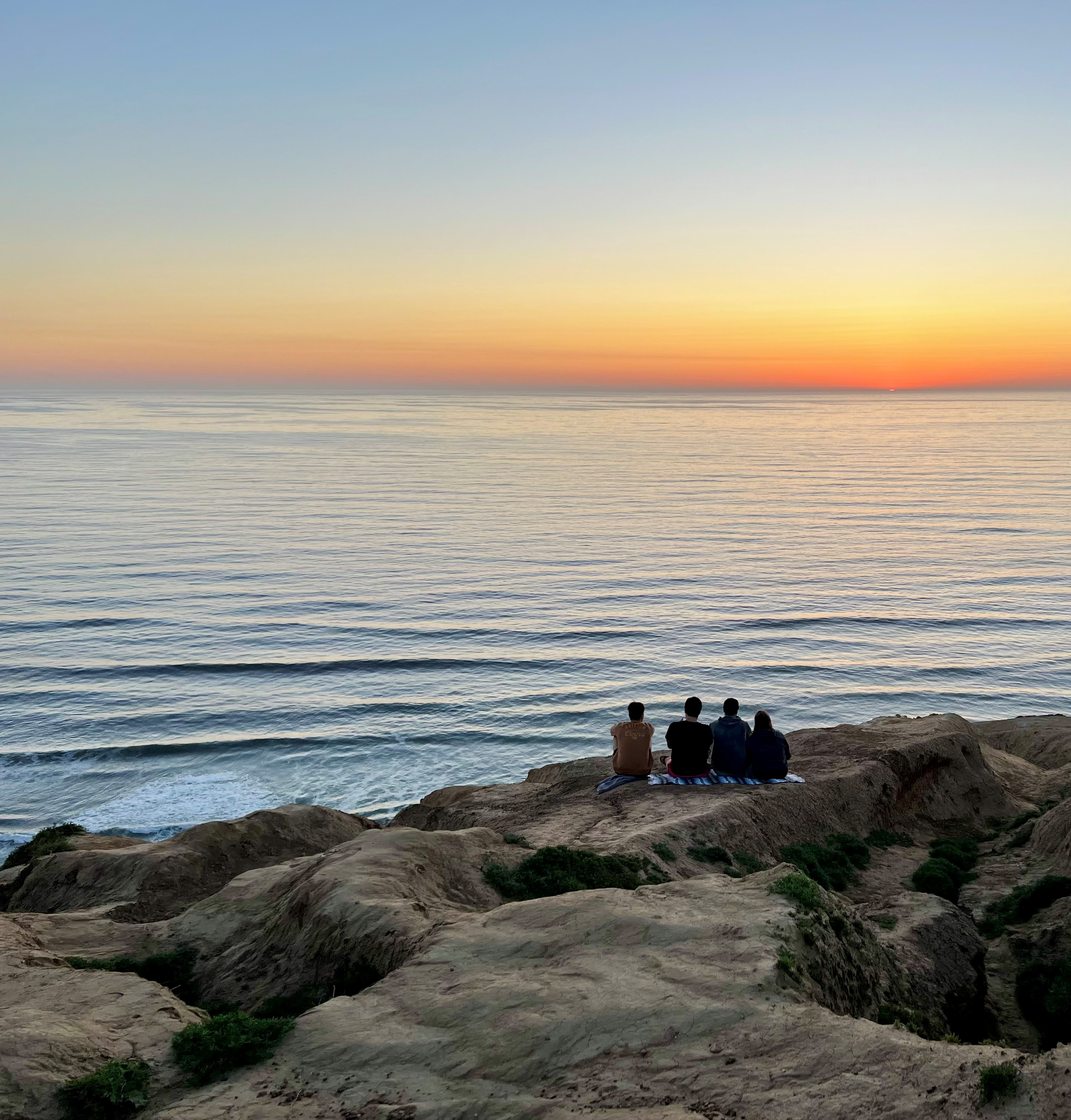 people sitting on a cliff watching a sunset in San Diego